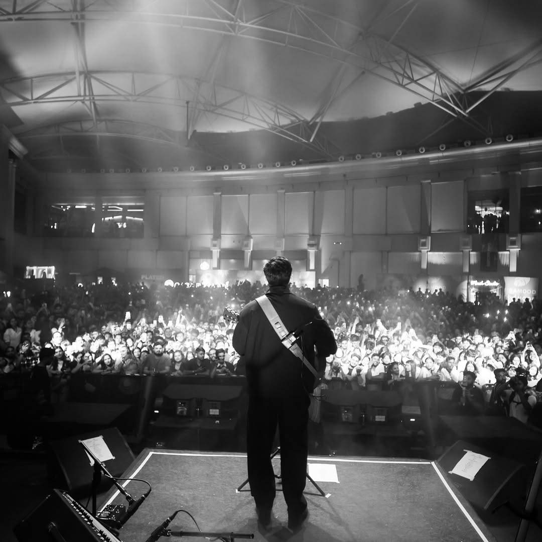 Anuv Jain performing live on stage with a crowd cheering in front of him